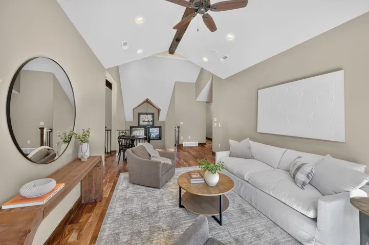 Vaulted ceilings, wood-finish flooring, recessed lighting, and a ceiling fan