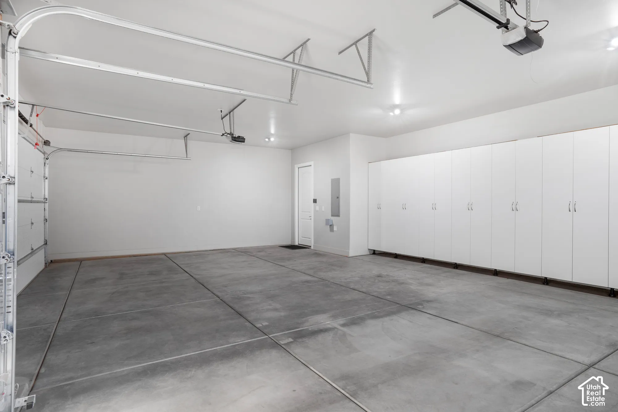 Spacious garage with extensive built-in cabinetry, concrete flooring, and overhead lighting
