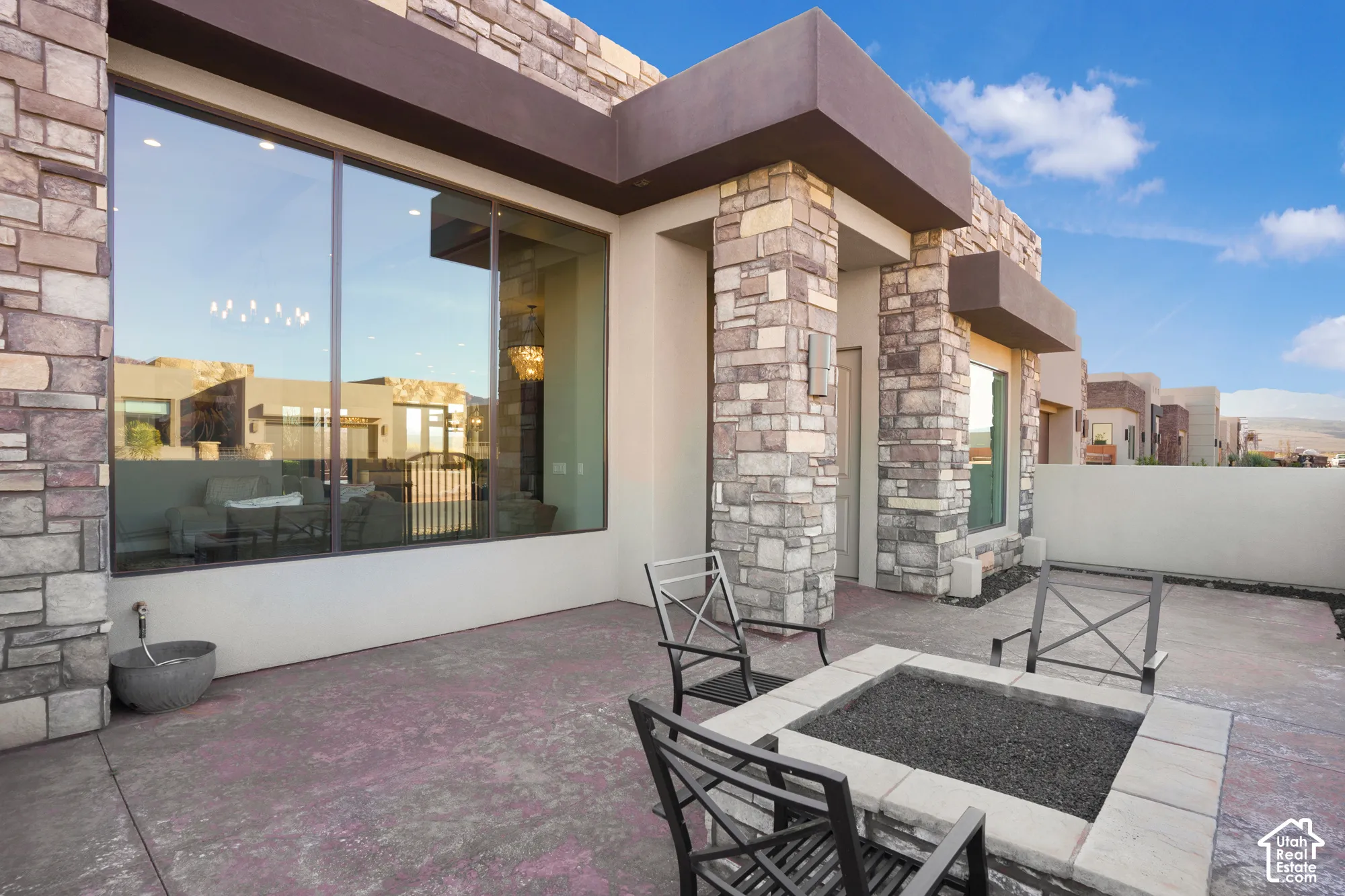 Expansive patio with a built-in fire pit, stone-clad exterior, and large picture windows