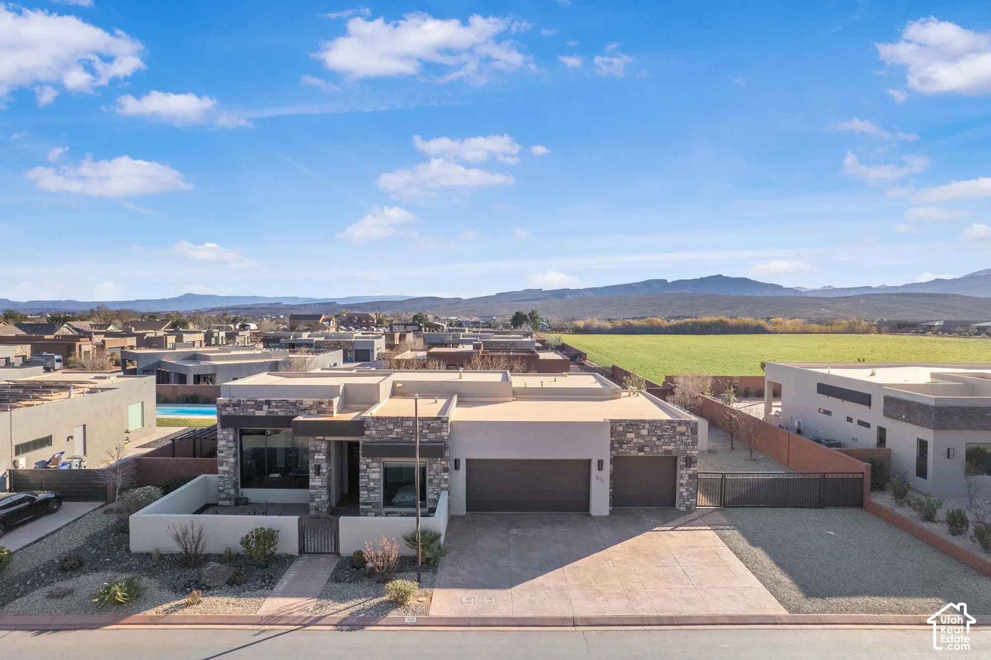 Contemporary residence featuring a flat roofline, stone and stucco exterior, two-car garage, and a gated side access