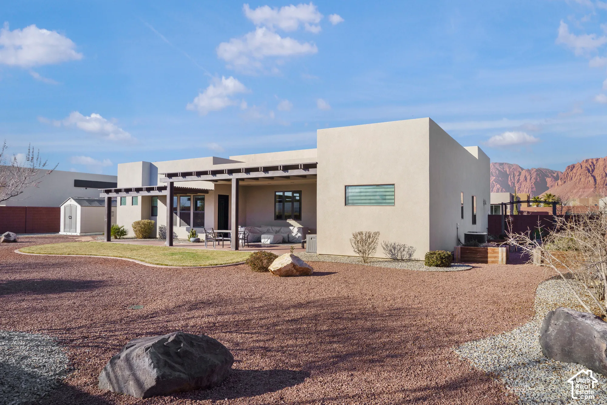 Stucco exterior with a flat roofline, showcasing a rear patio with a pergola