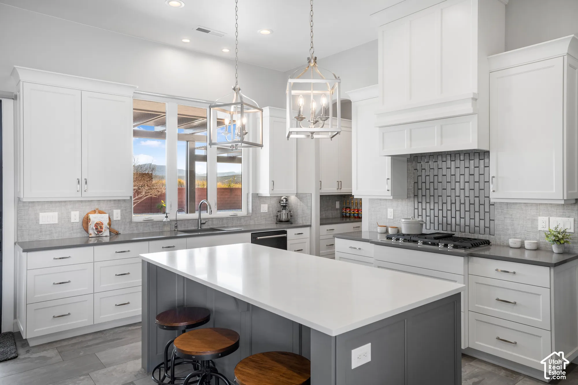Kitchen featuring a central island with a solid surface countertop, white cabinetry, dark countertops, a tile backsplash, and stainless steel appliances