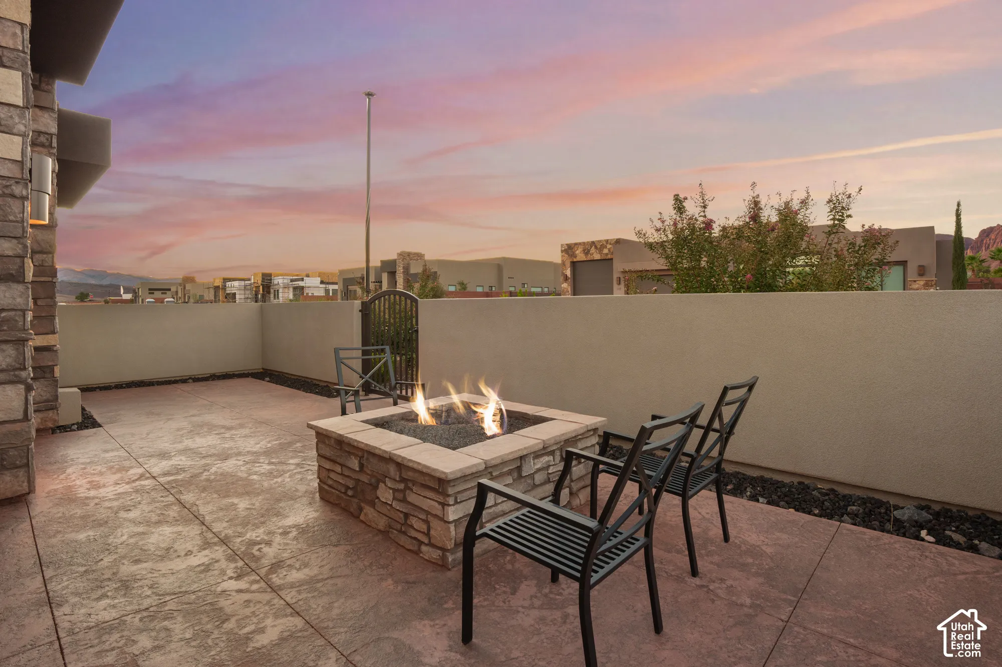Outdoor patio featuring a stone-clad fire pit, concrete flooring, and a low privacy wall