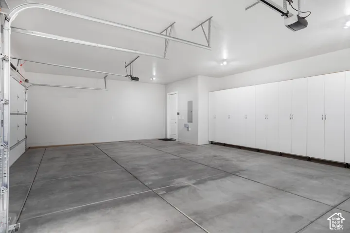 Spacious garage with extensive built-in cabinetry, concrete flooring, and overhead lighting
