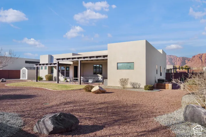 Stucco exterior with a flat roofline, showcasing a rear patio with a pergola