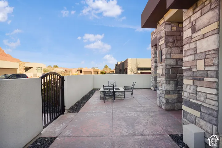 Stamped concrete patio featuring a stone-clad fire pit, wrought iron gate, and a stone-clad exterior