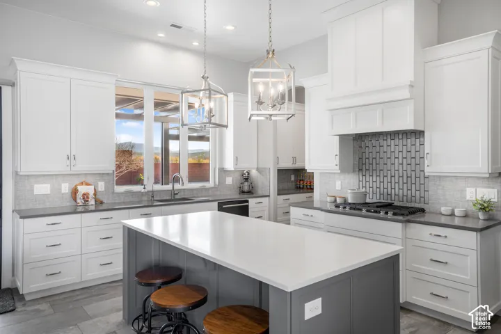 Kitchen featuring a central island with a solid surface countertop, white cabinetry, dark countertops, a tile backsplash, and stainless steel appliances