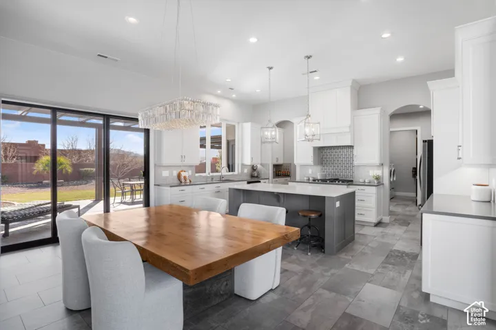 Spacious kitchen with a large center island, white cabinetry, tile backsplash, stainless steel appliances, and tile flooring