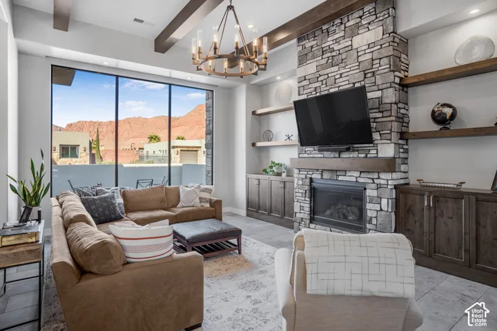 Expansive floor-to-ceiling windows, stone-clad fireplace, built-in shelving, custom cabinetry, and a decorative chandelier