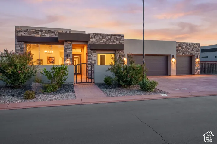 Stone veneer exterior with stucco accents, two-car garage, gated entry, and established landscaping
