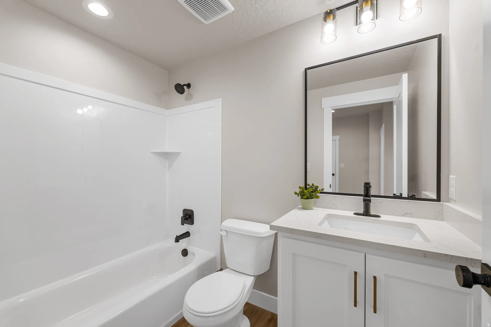 Bathroom featuring a white vanity with a rectangular undermount sink, a countertop with subtle veining, and a black-framed mirror