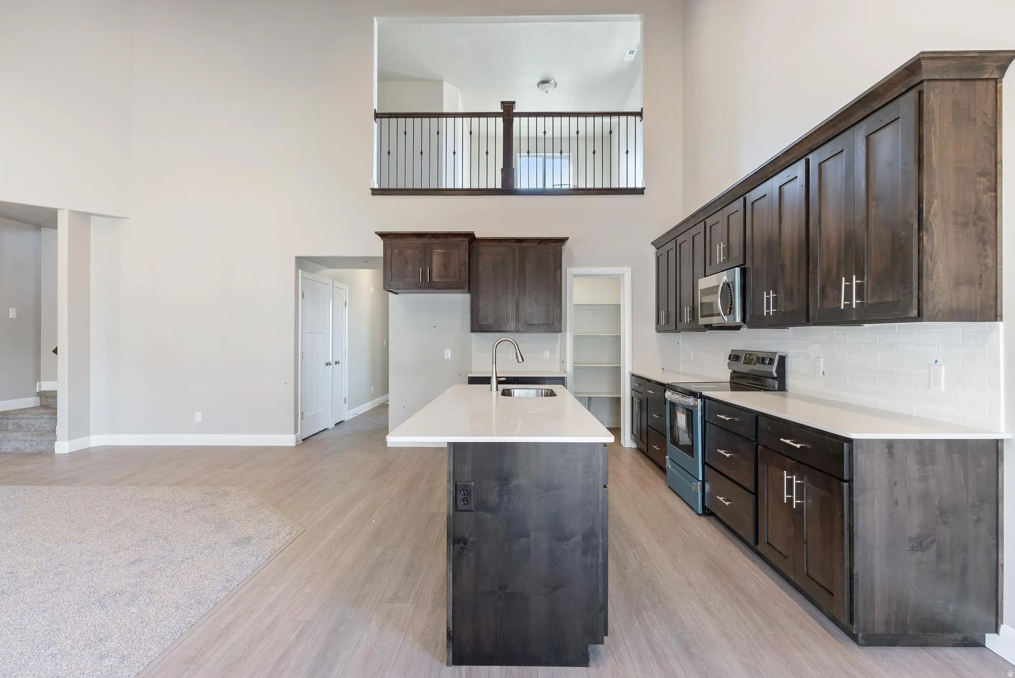 Open-concept kitchen with dark wood-finish cabinetry, white countertops, and a subway tile backsplash