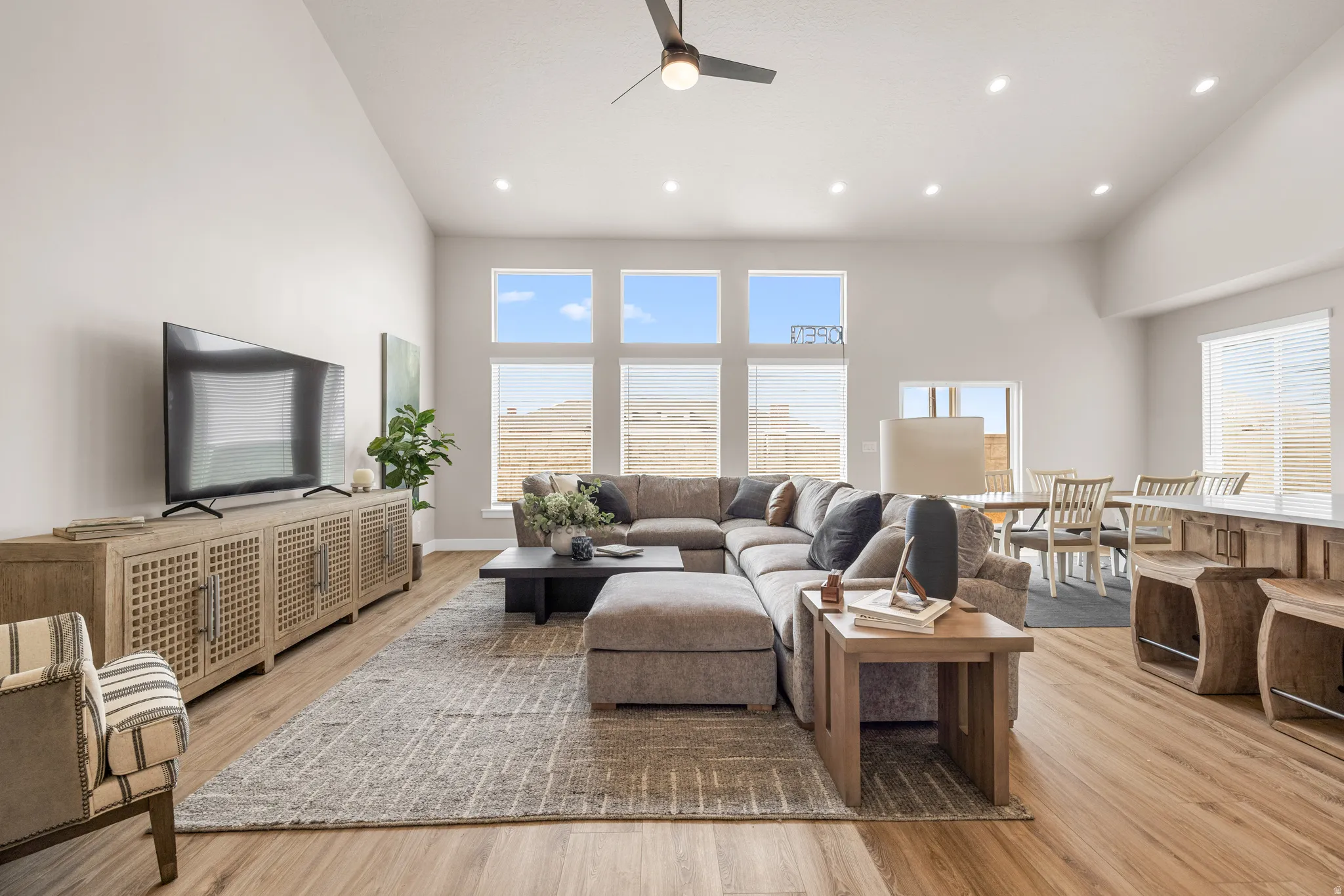 Vaulted ceilings, wood-finish flooring, recessed lighting, and large windows with horizontal blinds