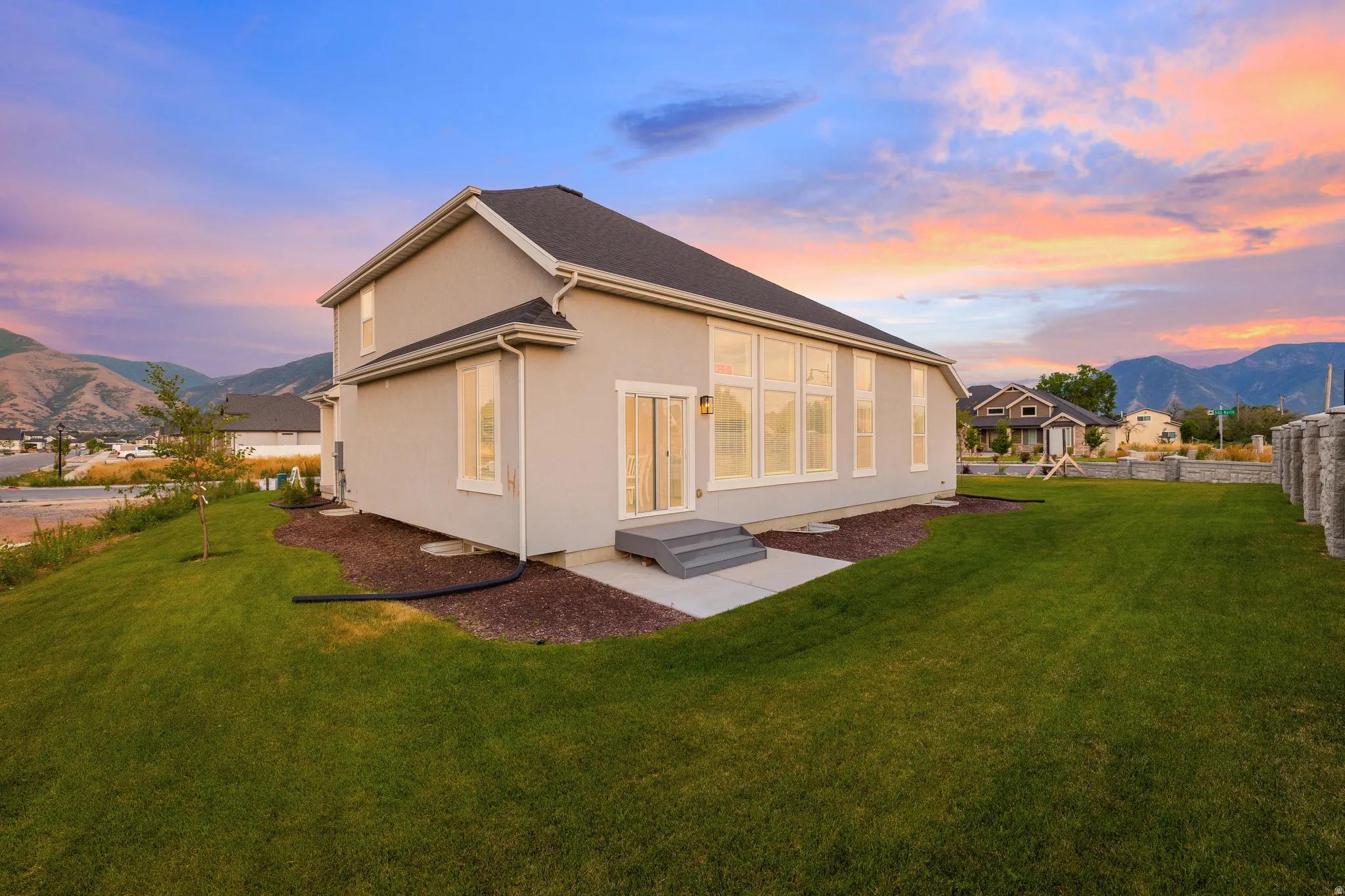 Expansive lawn with mature landscaping, a concrete patio, and sliding glass doors