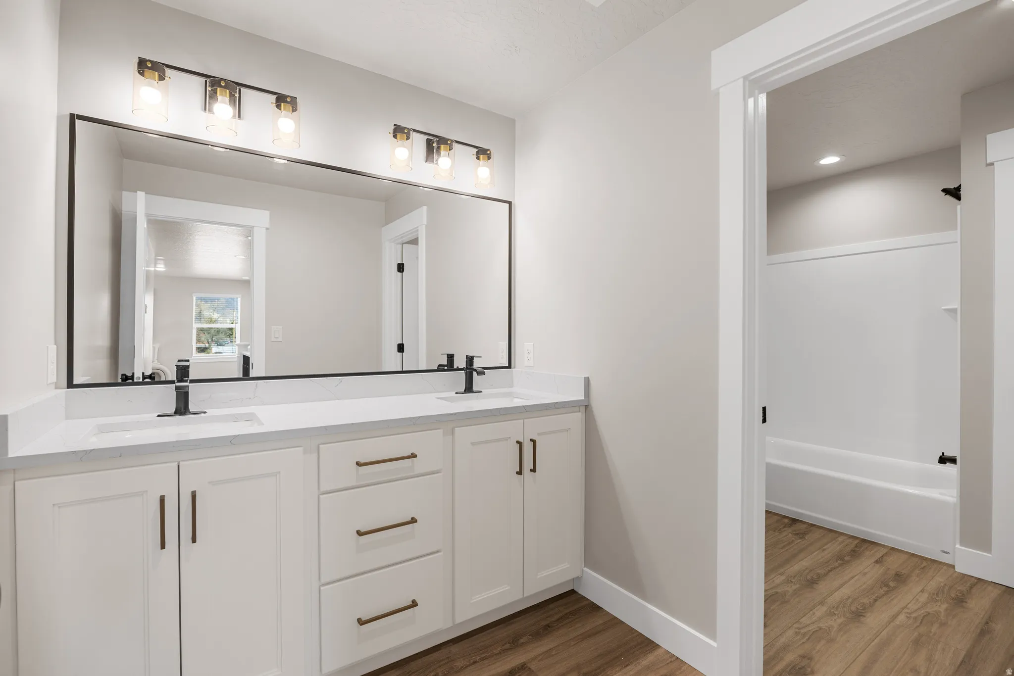 Double vanity with white cabinetry, matte black faucets, and a full-width mirror