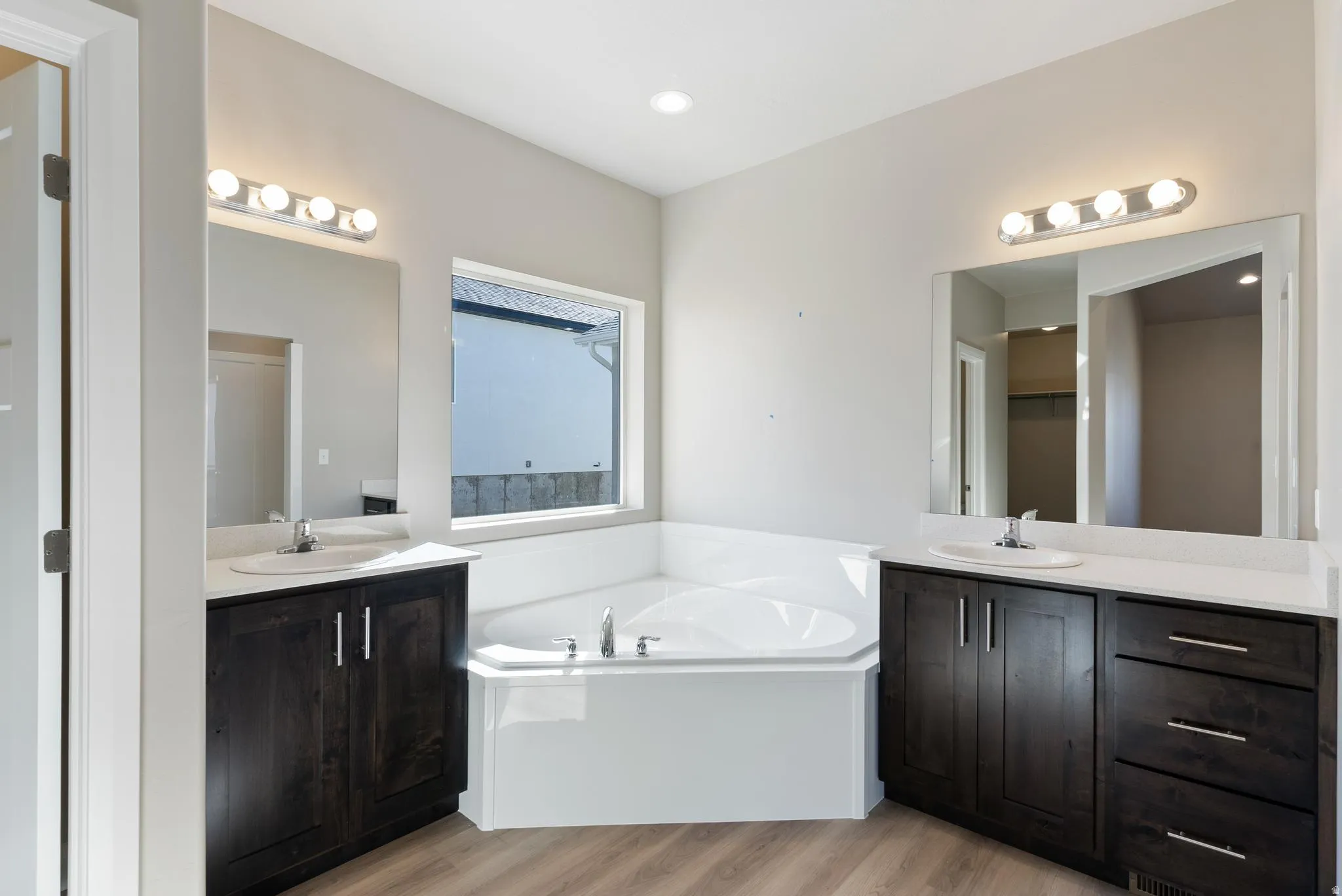 Dual vanities with undermount sinks, wood-finish cabinetry, and white countertops