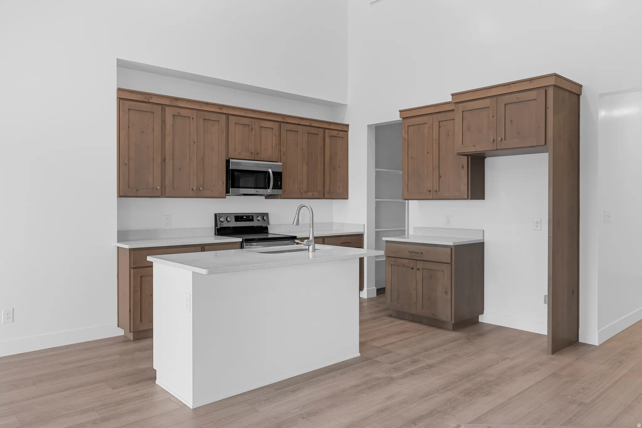 Kitchen featuring wood-finish cabinetry, stainless steel appliances, a center island with countertop, and wood-finish flooring