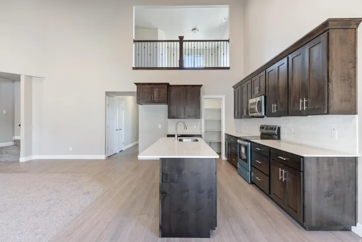 Open-concept kitchen with dark wood-finish cabinetry, white countertops, and a subway tile backsplash