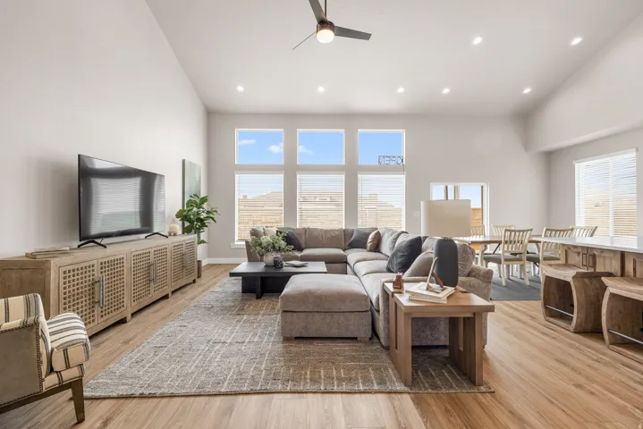 Vaulted ceilings, wood-finish flooring, recessed lighting, and large windows with horizontal blinds