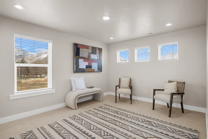Recessed lighting, large window, three smaller windows, neutral wall tones, and carpeted flooring