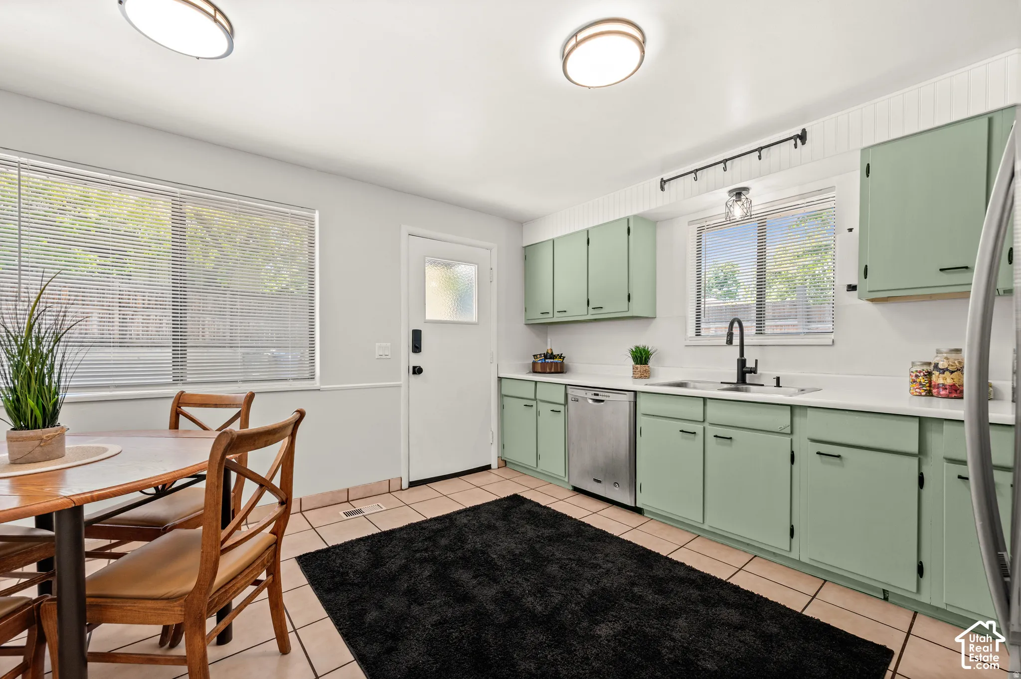 Kitchen featuring mint green cabinetry, white countertops, tile flooring, and a stainless steel dishwasher