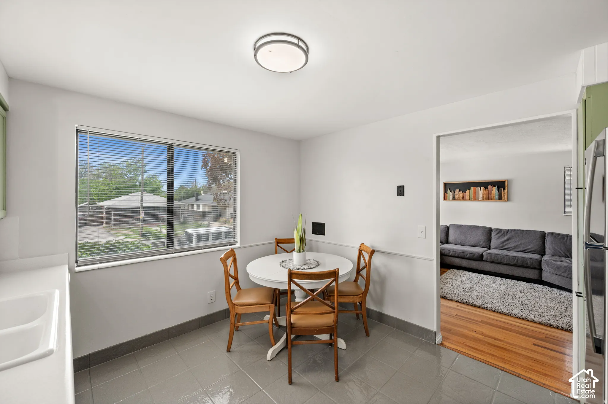 Bright dining area with tile flooring, a large window, and wainscoting