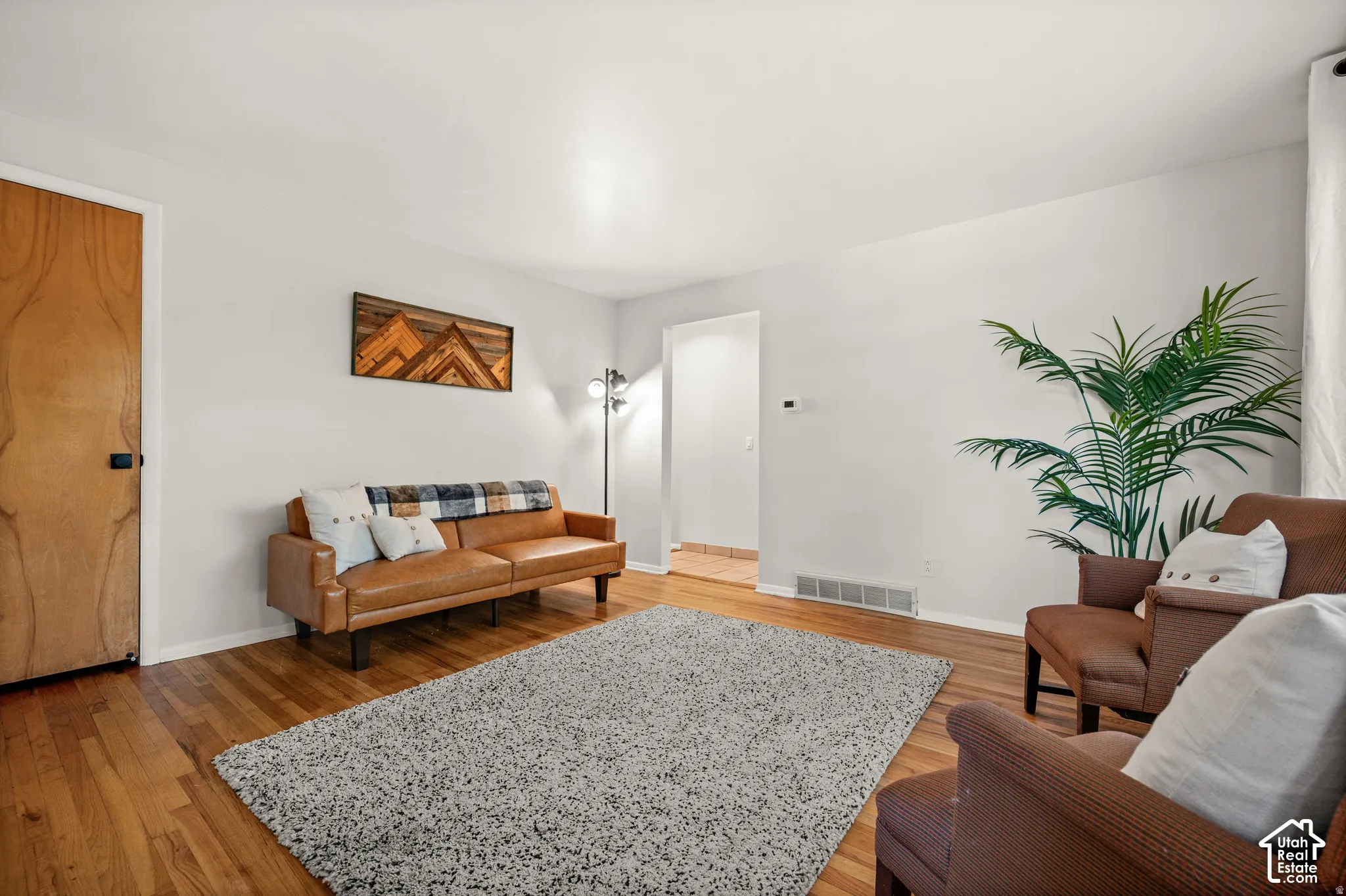 Hardwood flooring, light-toned wall finishes, and a wood-paneled interior door