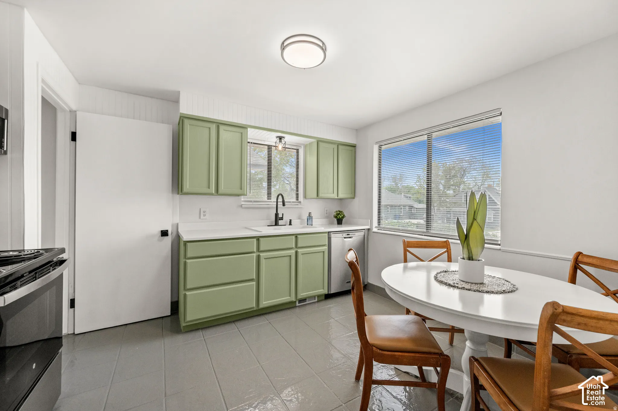Kitchen featuring light green cabinetry, white countertops, tile flooring, and a large window