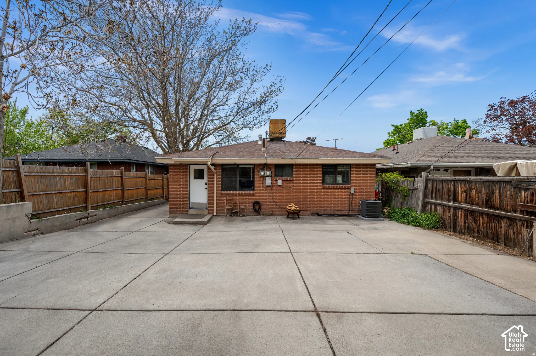 Concrete paving throughout, brick exterior, and a wood privacy fence