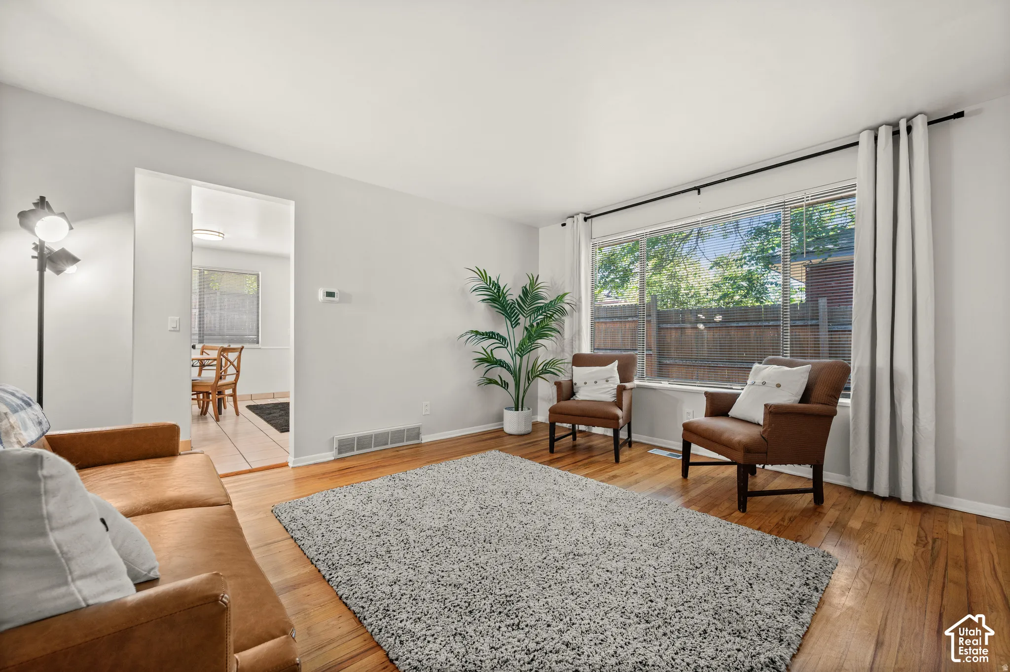 Hardwood-style flooring throughout, with a large picture window, and a spacious doorway to an additional room featuring tile flooring