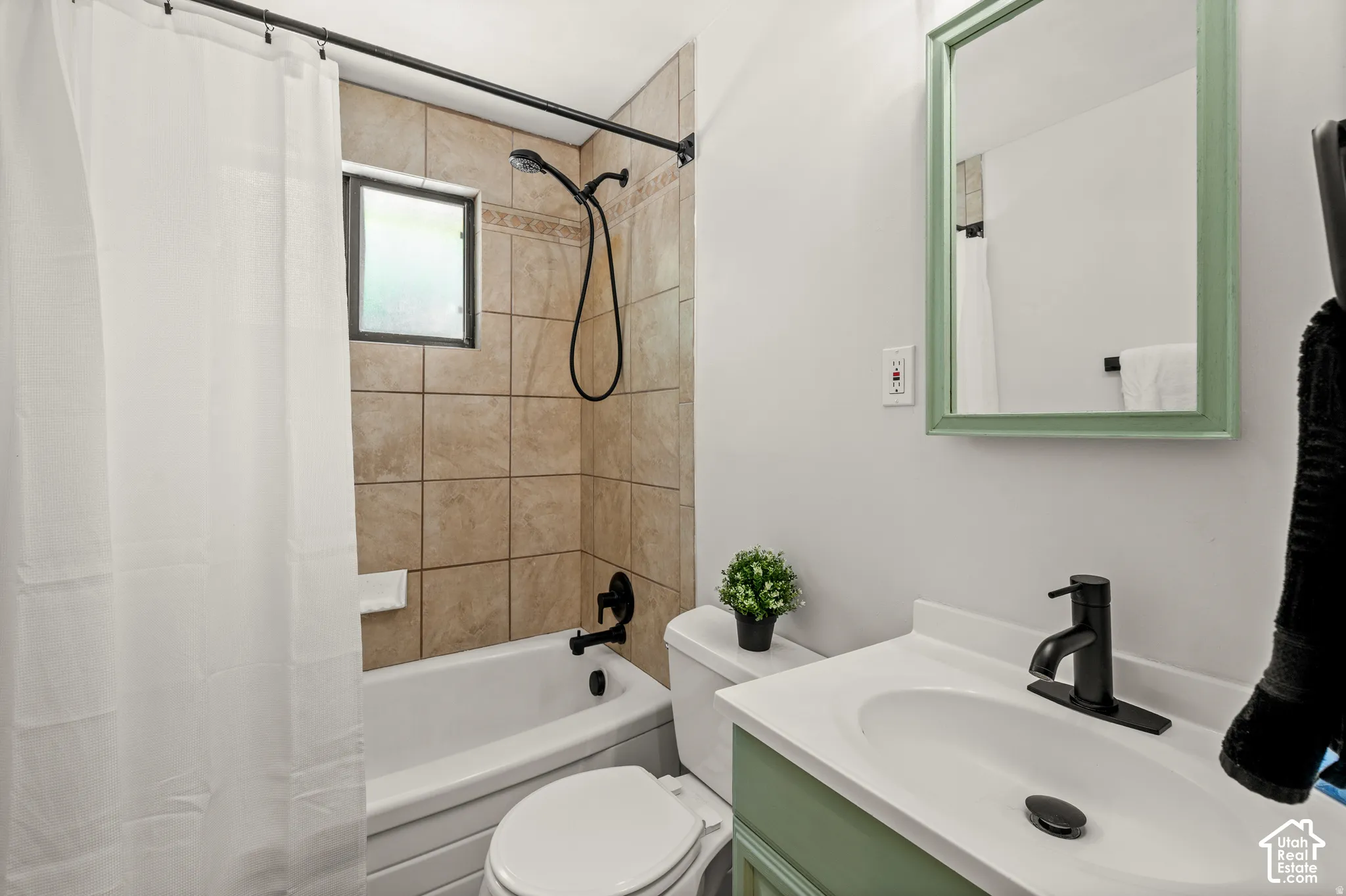 Built-in bathtub with a tile surround, black-finish shower fixtures, and a window
