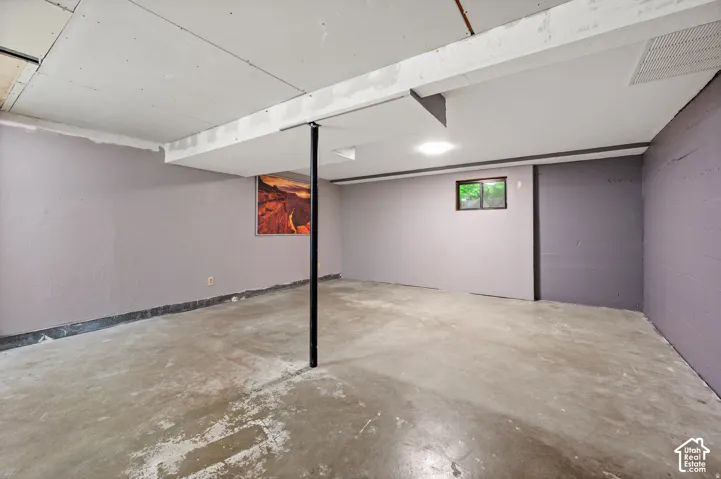 Finished concrete flooring with exposed ceiling beams and recessed lighting
