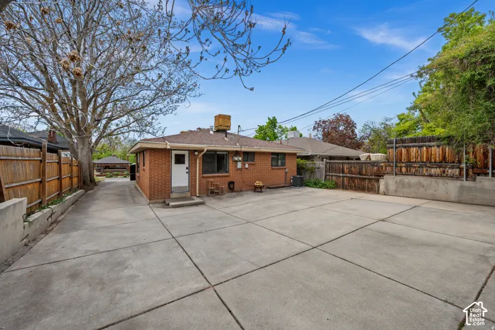 Expansive concrete patio with brick exterior and wood fencing