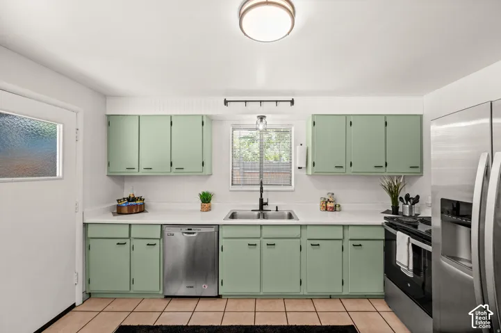 Kitchen featuring green cabinetry, light-colored countertops, stainless steel appliances, and tile flooring