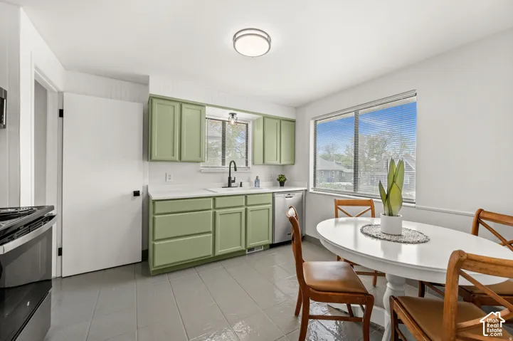 Kitchen featuring light green cabinetry, white countertops, tile flooring, and a large window