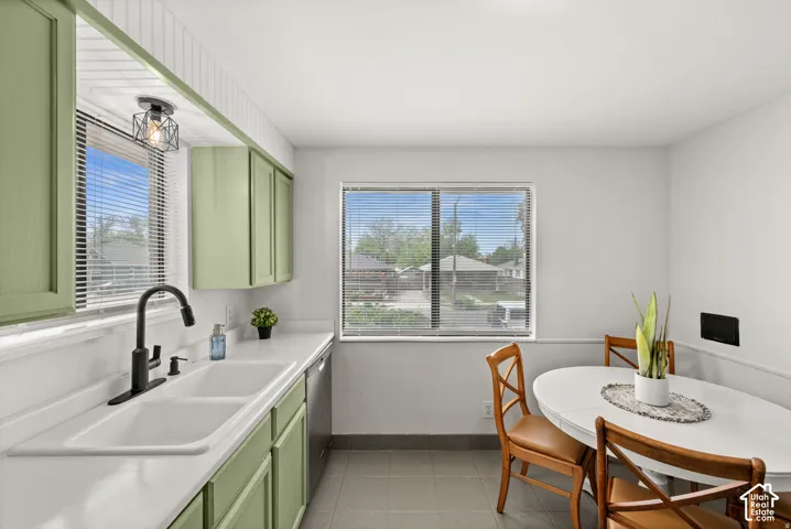 Kitchen with dual basin sink, black gooseneck faucet, light green cabinetry, and a tile floor