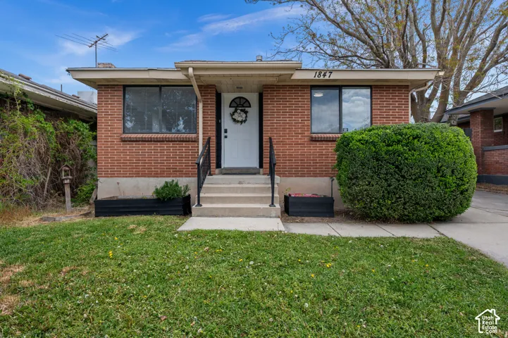 Brick exterior with a white entry door, concrete steps, and black handrails