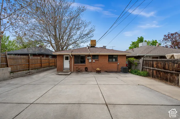 Concrete paving throughout, brick exterior, and a wood privacy fence