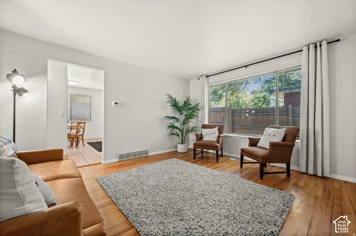 Hardwood-style flooring throughout, with a large picture window, and a spacious doorway to an additional room featuring tile flooring