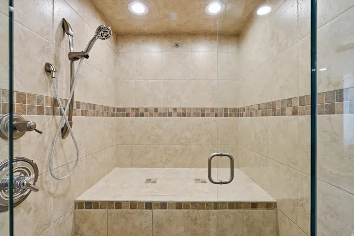 Walk-in shower with full tile surround, integrated bench, and clear glass enclosure