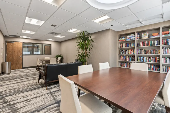 Built-in shelving, wood-finish door, patterned carpet, recessed ceiling lighting, and large windows