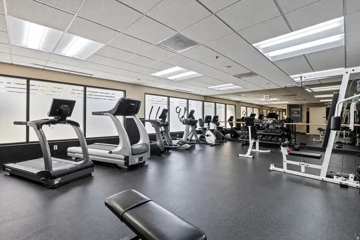 Fitness center with extensive cardio equipment, strength training machines, free weights, and resilient rubber flooring