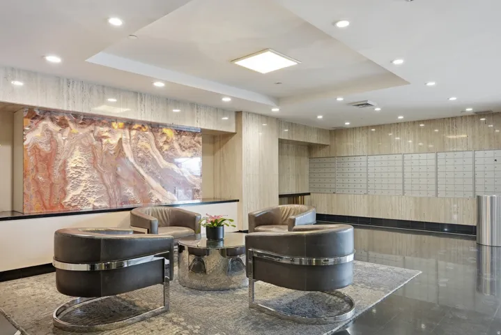 Lobby area featuring polished dark flooring, a textured accent wall, and recessed lighting