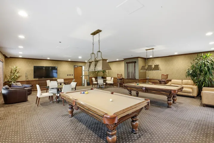 Spacious recreation area featuring two billiards tables and plenty of couches.