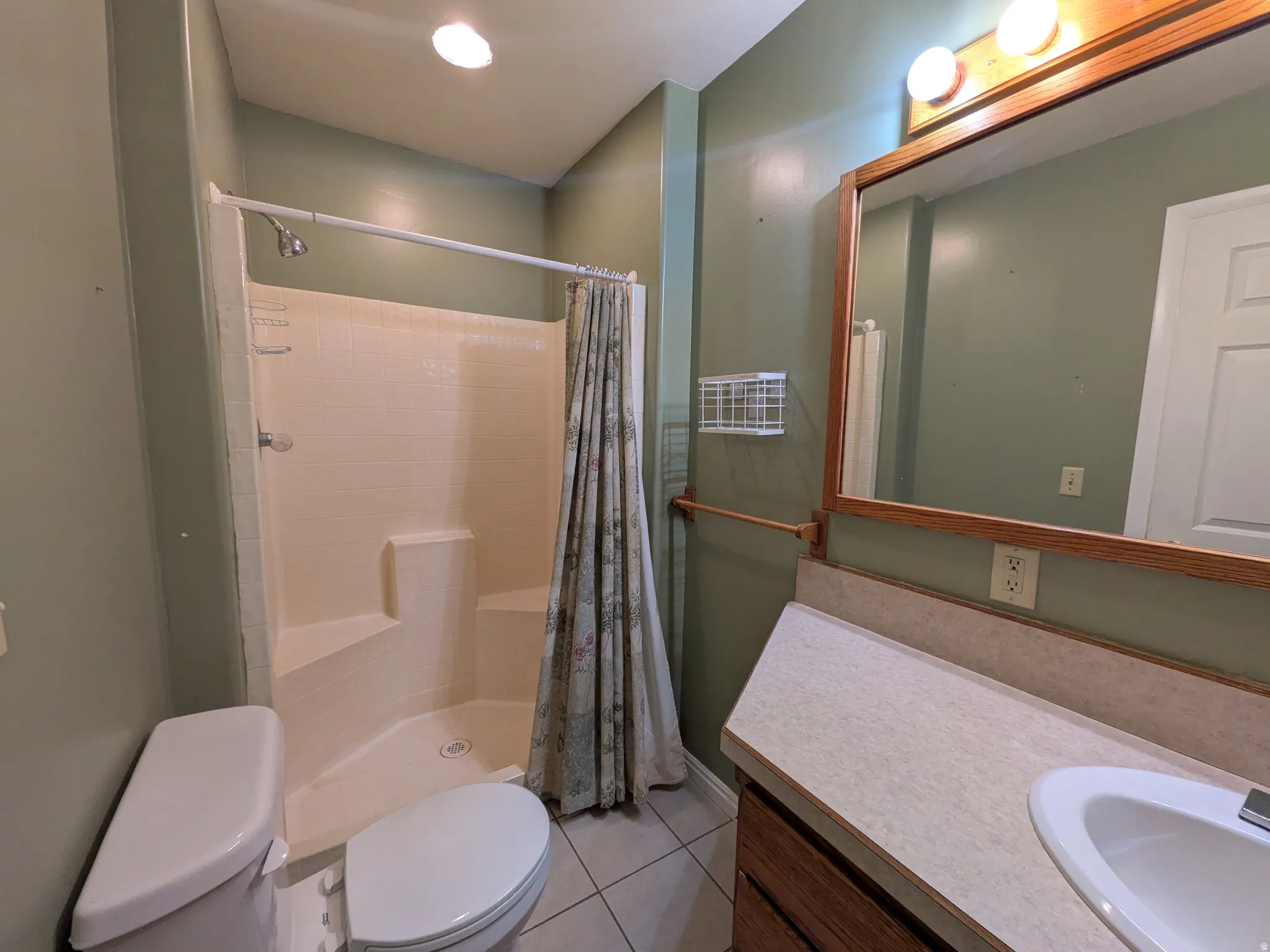 Shower with integrated seating, single vanity with laminate countertop, wood-framed mirror, and recessed ceiling lighting