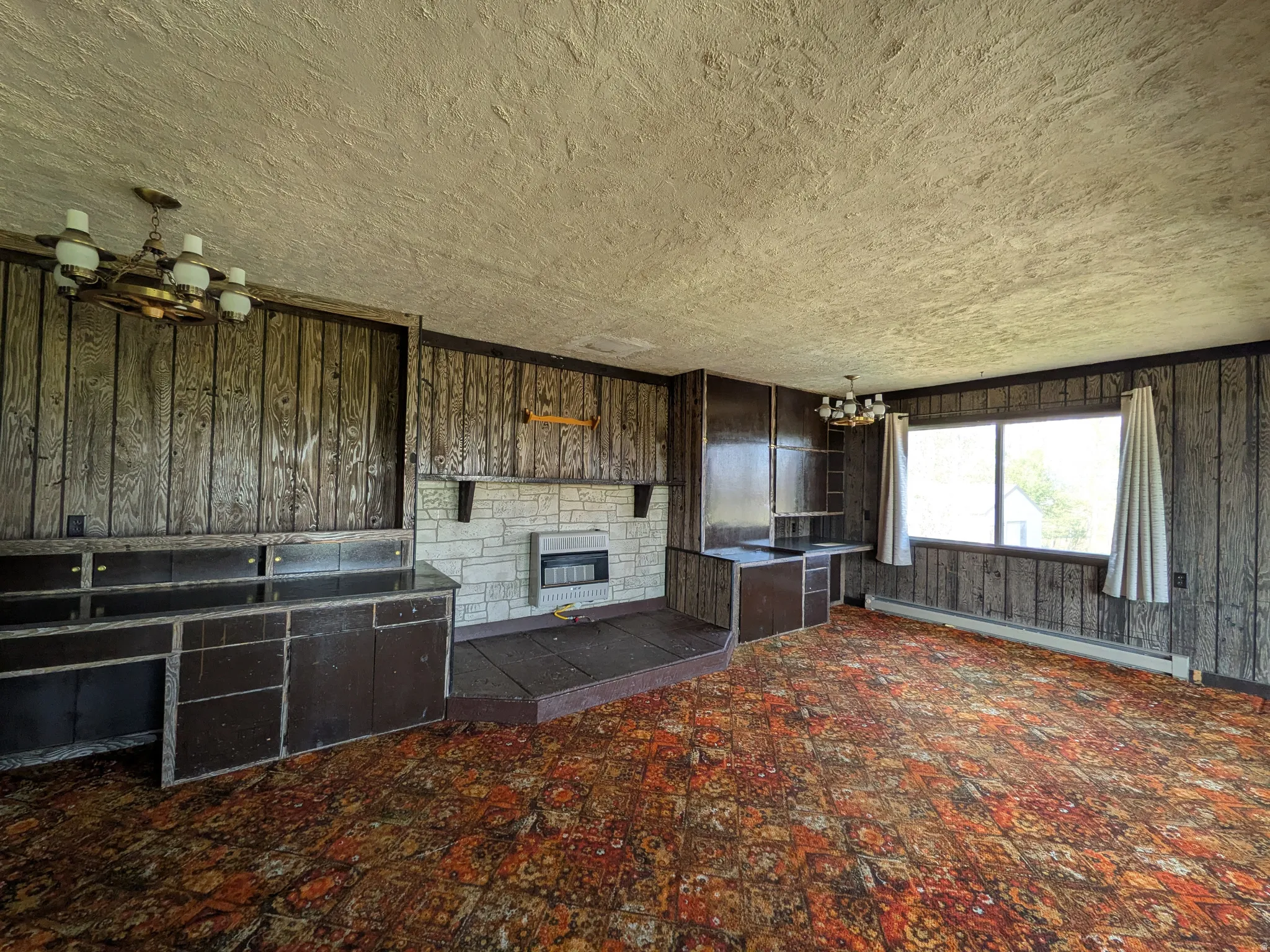 Wall-to-wall carpeting, wood paneling, built-in cabinetry, stone-clad fireplace, and multiple windows