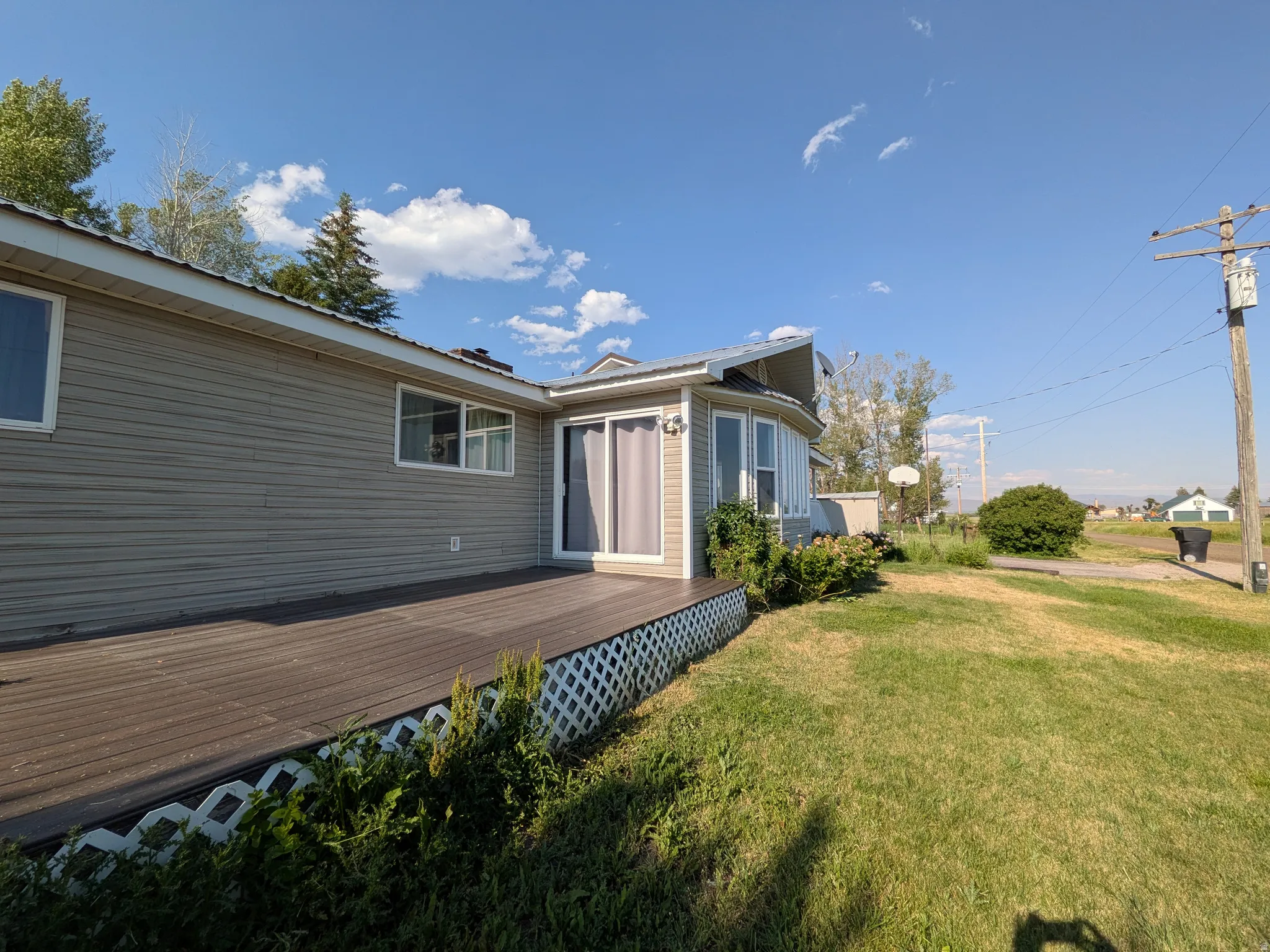 Exterior featuring neutral-toned siding, a spacious composite deck, multiple windows, and a curved window bay