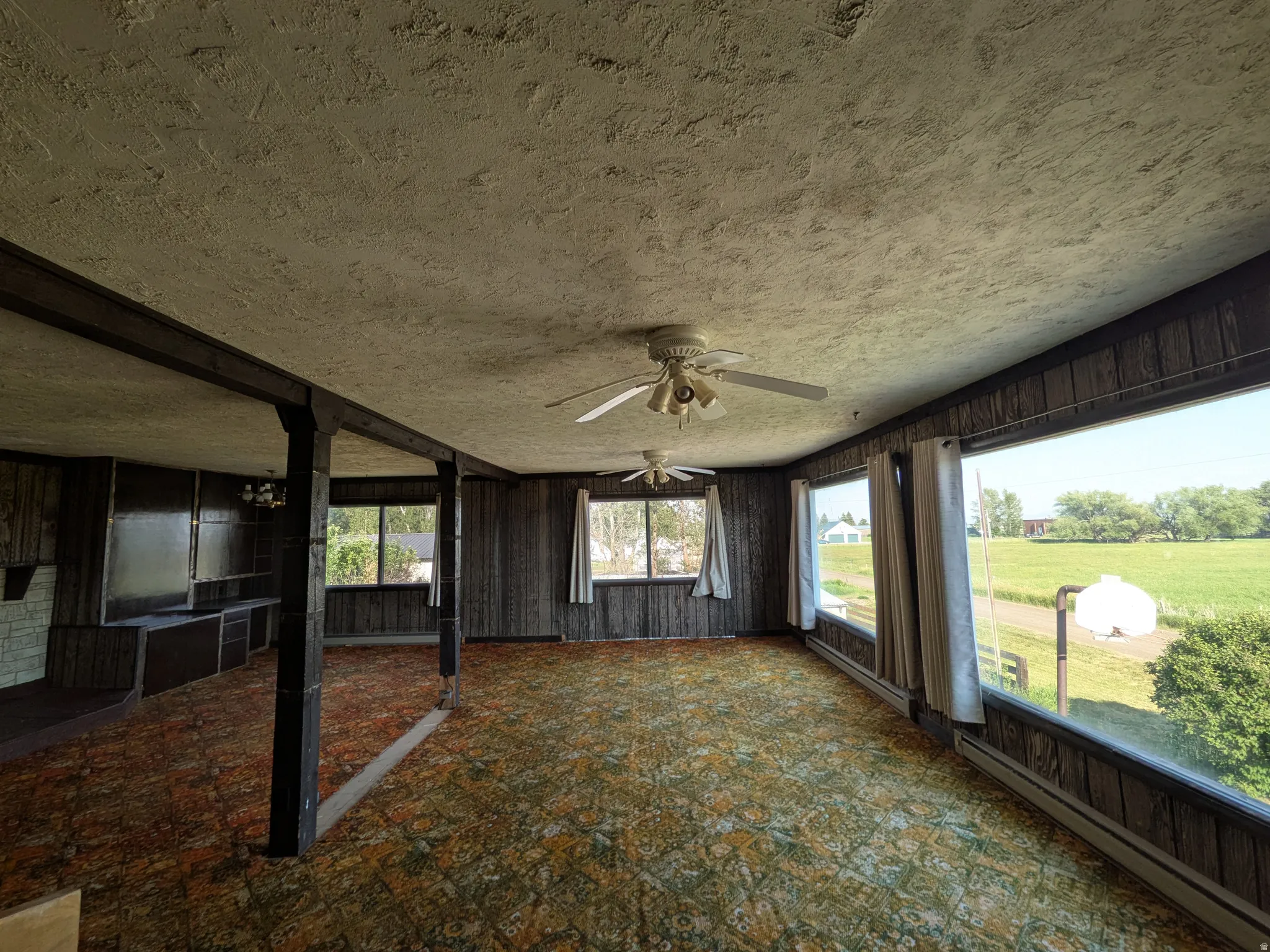 Room with wood-panel walls, patterned carpet, and multiple ceiling fans