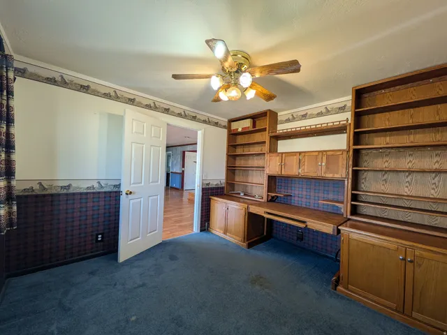 Built-in wood cabinetry with integrated desk space and shelving, ceiling fan with light kit, and paneled interior door