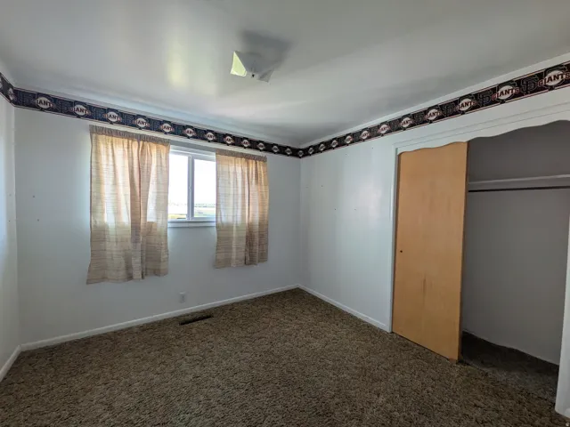 Bright interior with white walls, a single window, and a built-in closet featuring a sliding wood-finish door